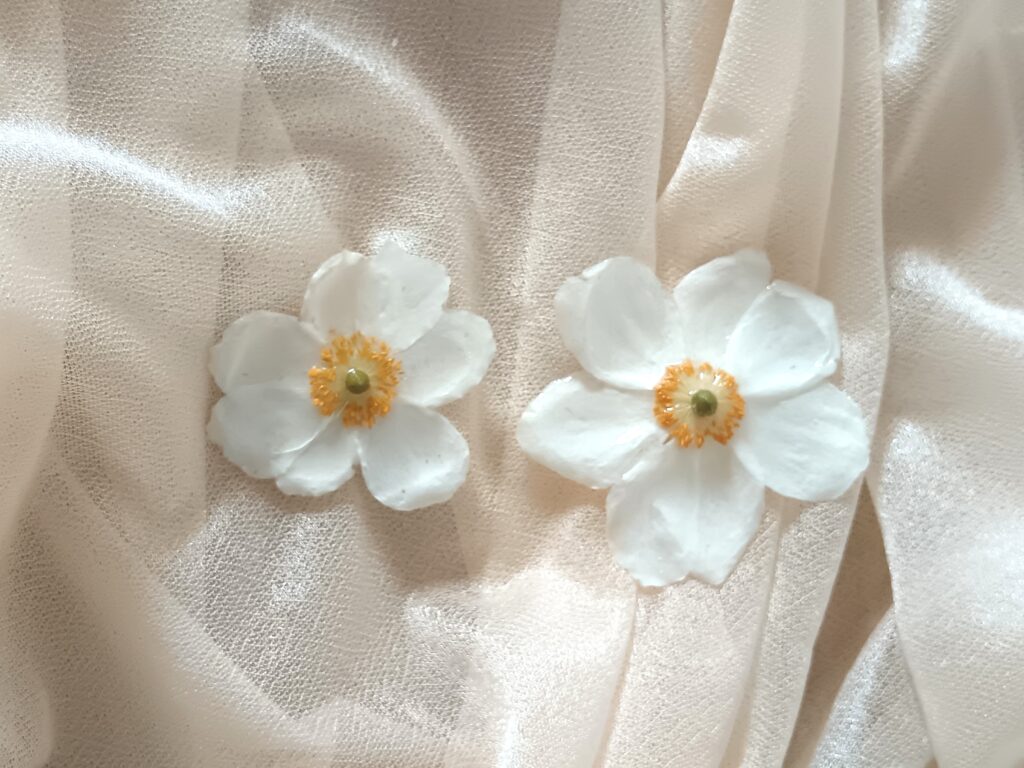 Fleurs blanches cristallisées posées sur un tissu beige, créations florales artisanales réalisées avec une technique de préservation délicate fait par Invitation Florale en Normandie.