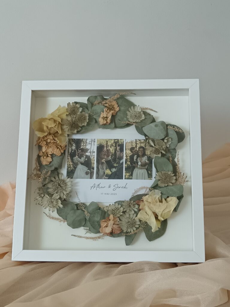 Cadre souvenir de mariage avec fleurs séchées et photos du couple – création personnalisée par Invitation Florale. Conservation de bouquet de mariée en cadre rond, eucalyptus et fleurs naturelles séchées.